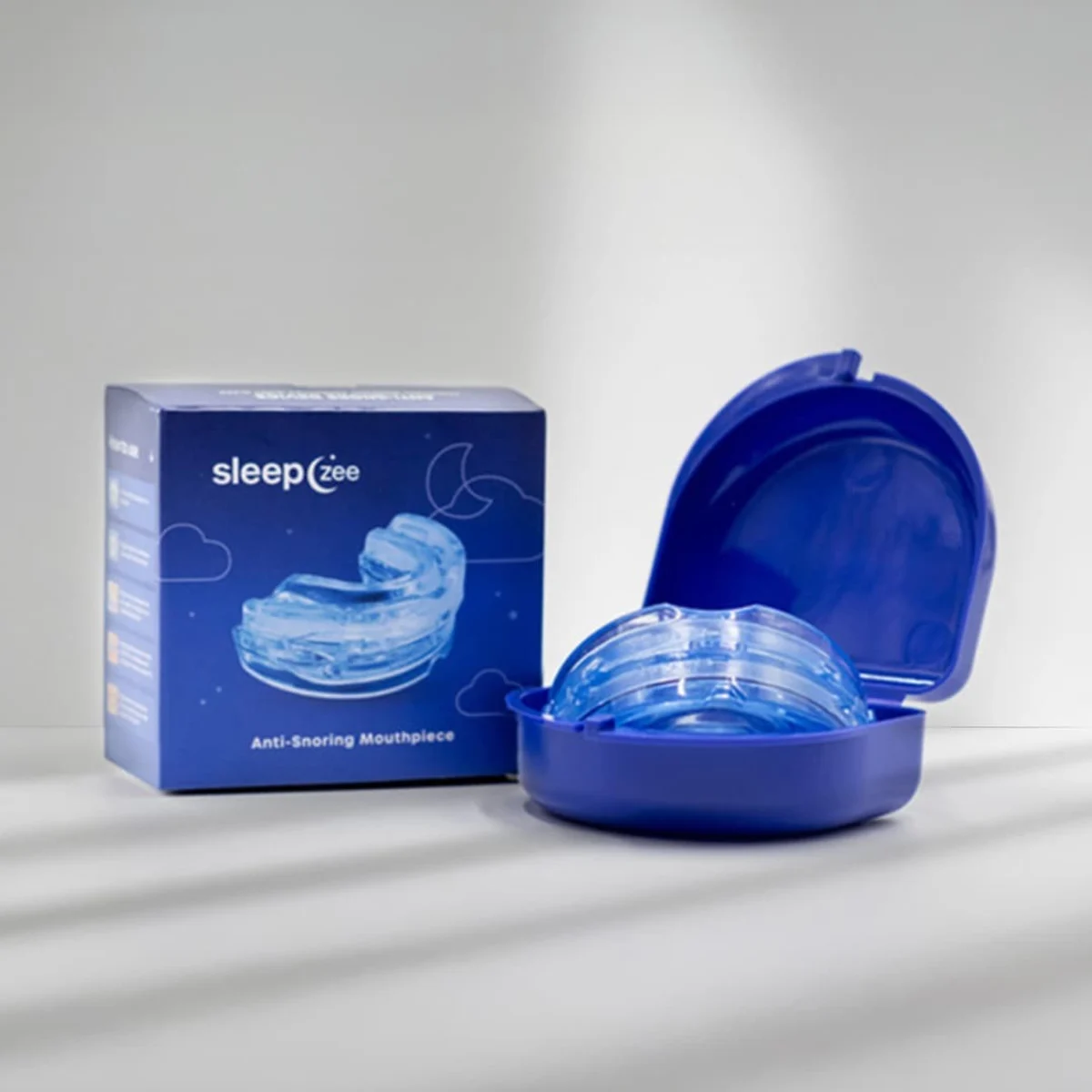 Sleepzee anti-snoring mouthpiece in a blue carrying case beside its packaging